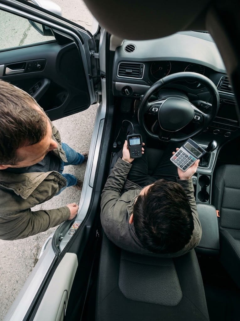 A Car4Pro advisor reads a diagnostic scanner and works out a price inside a seller’s car